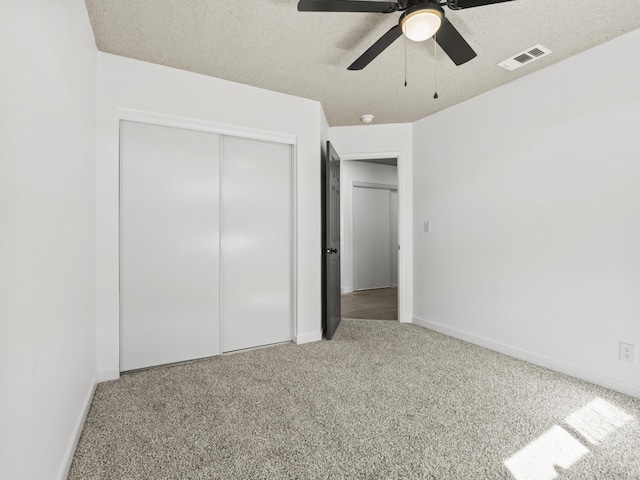 unfurnished bedroom featuring carpet flooring, ceiling fan, a closet, and a textured ceiling