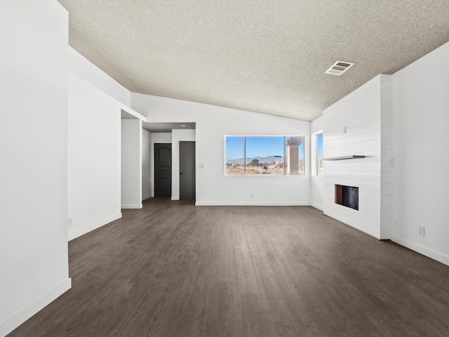 unfurnished living room with a textured ceiling, a large fireplace, dark wood-type flooring, and vaulted ceiling