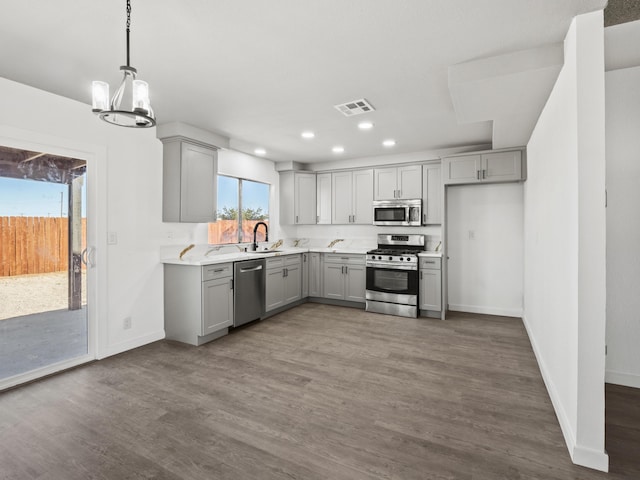 kitchen with gray cabinetry, stainless steel appliances, sink, an inviting chandelier, and dark hardwood / wood-style floors