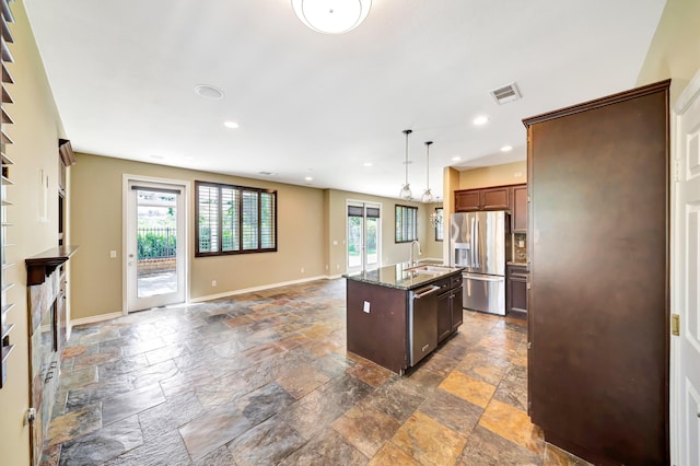 27735 Summer Grove Pl, Valencia, CA 91354 - kitchen featuring appliances with stainless steel finishes, stone tile floors, a kitchen island with sink, dark stone countertops, and recessed lighting