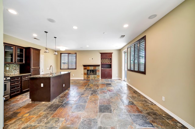 27735 Summer Grove Pl, Valencia, CA 91354 - kitchen featuring stone tile floors, baseboards, a sink, glass insert cabinets, and a fireplace