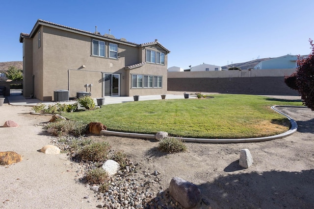 rear view of house featuring central air condition unit and a yard