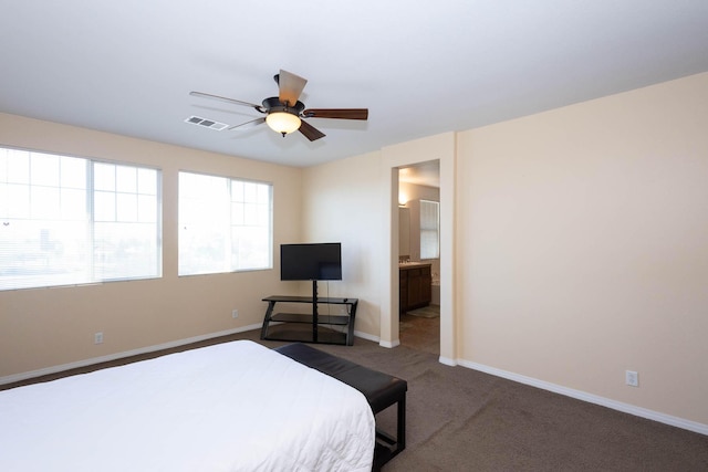 carpeted bedroom featuring multiple windows, ensuite bathroom, and ceiling fan