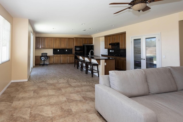 living room featuring ceiling fan, a healthy amount of sunlight, sink, and french doors