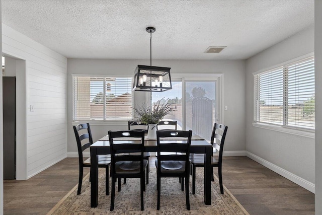 44850 E 43rd St, Lancaster, CA 93535 - dining space featuring a textured ceiling, wood finished floors, a chandelier, baseboards, and wood walls