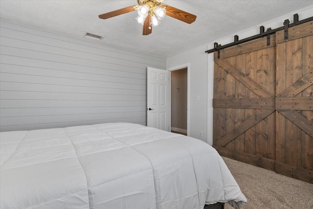 44850 E 43rd St, Lancaster, CA 93535 - carpeted bedroom with a textured ceiling, a barn door, a ceiling fan, and wood walls