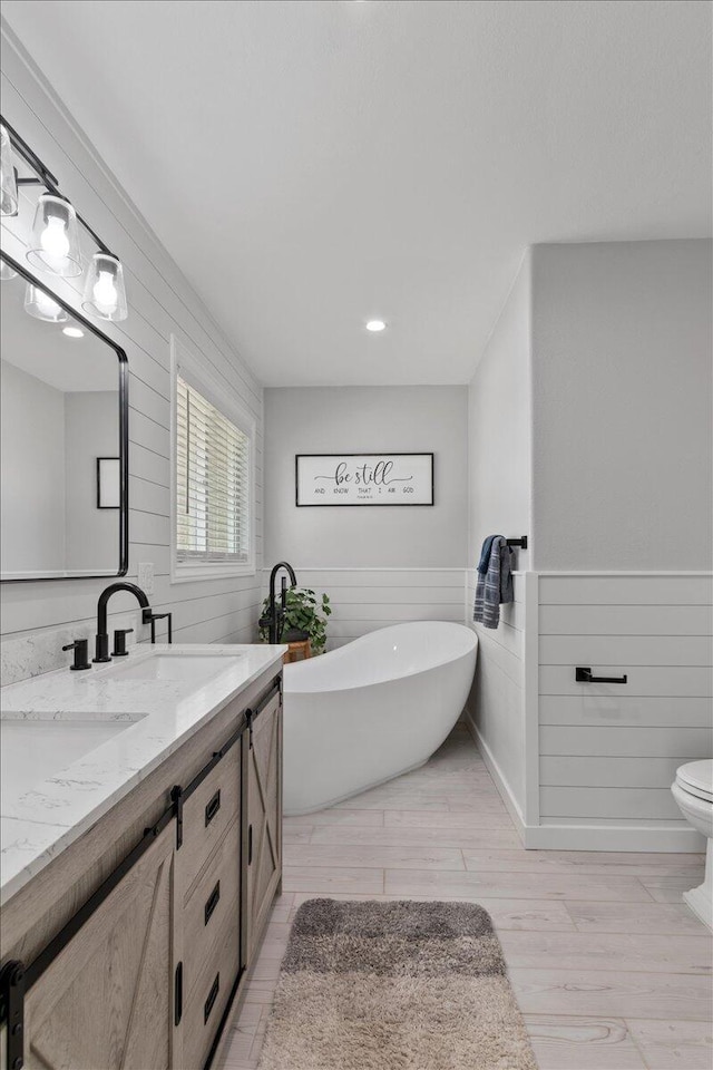 44850 E 43rd St, Lancaster, CA 93535 - full bath featuring wood finished floors, a freestanding tub, double vanity, wainscoting, and toilet