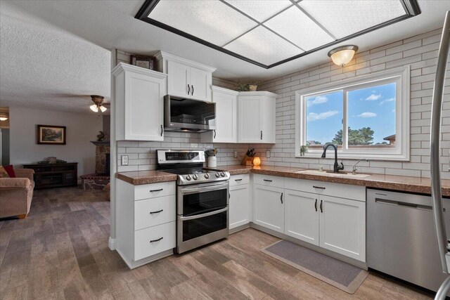 44850 E 43rd St, Lancaster, CA 93535 - kitchen featuring stainless steel appliances, a sink, decorative backsplash, light wood-style floors, and a textured ceiling