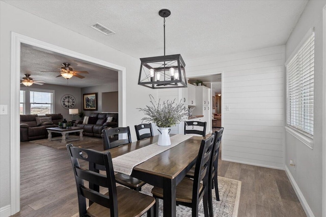44850 E 43rd St, Lancaster, CA 93535 - dining area with a textured ceiling, dark wood-style floors, ceiling fan, baseboards, and wood walls