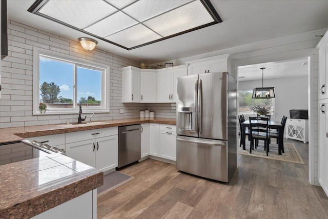 44850 E 43rd St, Lancaster, CA 93535 - kitchen featuring appliances with stainless steel finishes, a sink, light wood-type flooring, and white cabinetry