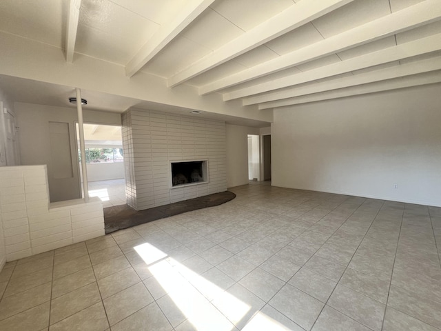 unfurnished living room with beamed ceiling, light tile patterned floors, and a brick fireplace