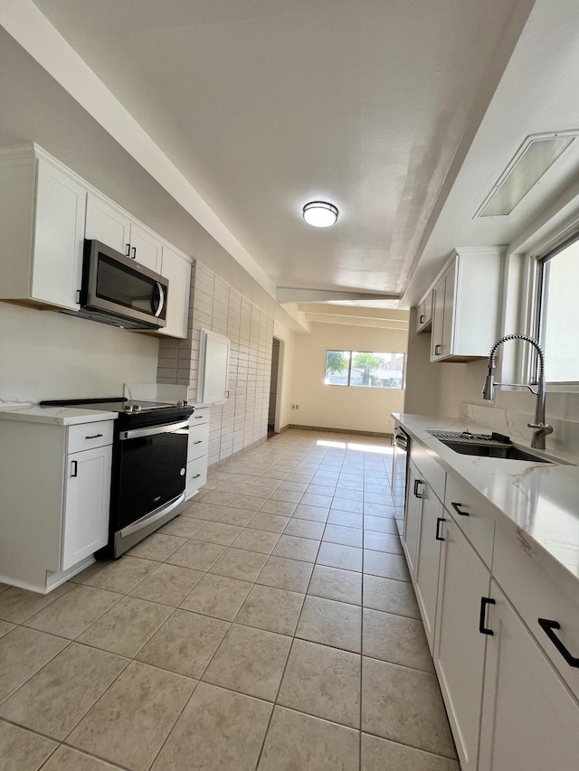 kitchen featuring light tile patterned flooring, appliances with stainless steel finishes, white cabinetry, and sink