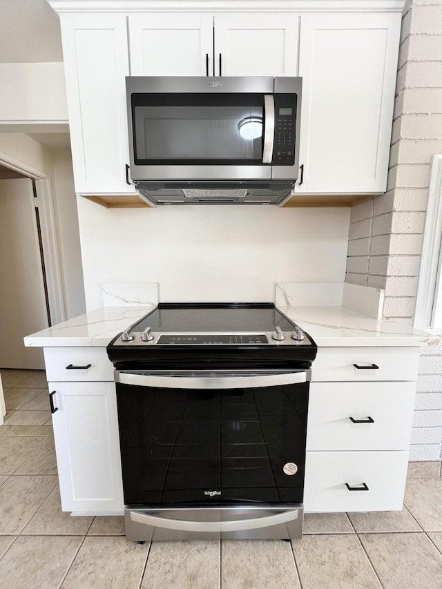 kitchen with white cabinetry, stainless steel appliances, light tile patterned floors, and tasteful backsplash