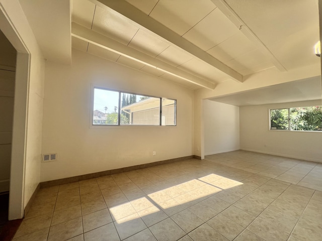 additional living space with vaulted ceiling with beams, light tile patterned floors, and a healthy amount of sunlight