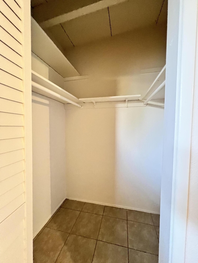 walk in closet with dark tile patterned flooring