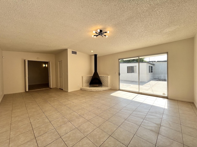 unfurnished living room featuring light tile patterned floors, a textured ceiling, and a wood stove