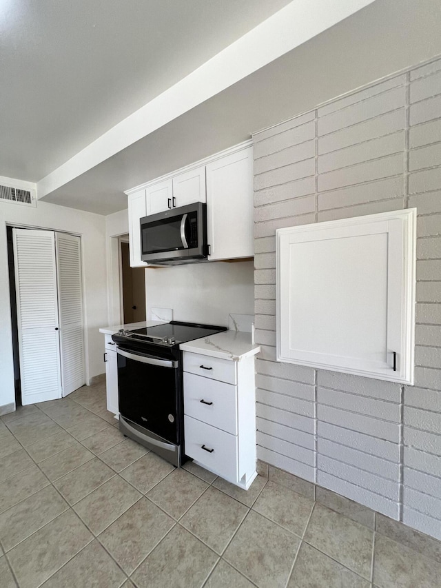 kitchen with light tile patterned flooring, white cabinetry, and appliances with stainless steel finishes