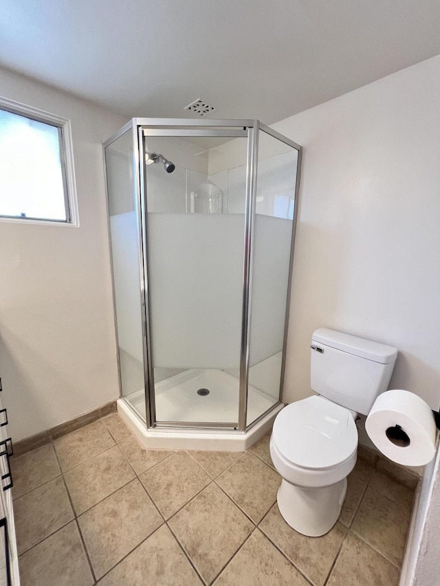 bathroom with tile patterned flooring, a shower with shower door, and toilet