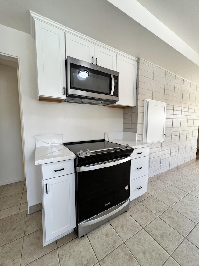 kitchen featuring light tile patterned floors, white cabinetry, and range with electric stovetop