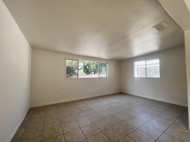 unfurnished room with light tile patterned floors and a textured ceiling