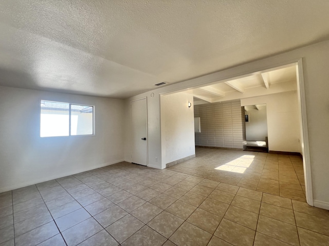 spare room with light tile patterned flooring and a textured ceiling