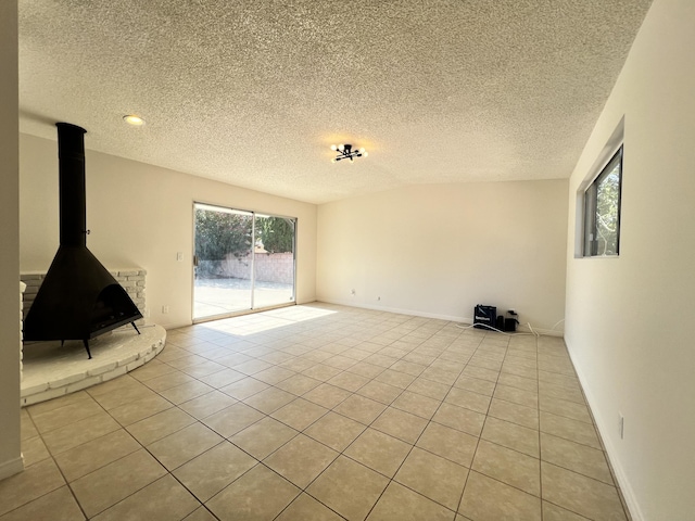 unfurnished living room with light tile patterned floors, a textured ceiling, and a wood stove