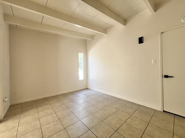 empty room with beamed ceiling and light tile patterned floors