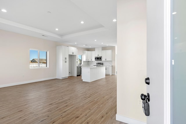 unfurnished living room featuring light hardwood / wood-style floors and a raised ceiling