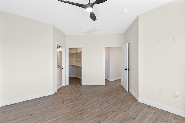 unfurnished bedroom featuring a closet, ceiling fan, light hardwood / wood-style flooring, and a spacious closet