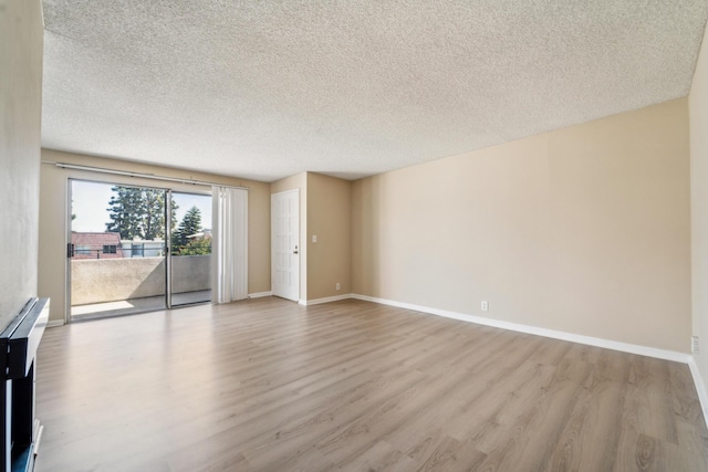 unfurnished room featuring a textured ceiling, wood finished floors, and baseboards