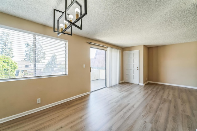 unfurnished room featuring a textured ceiling, baseboards, and wood finished floors