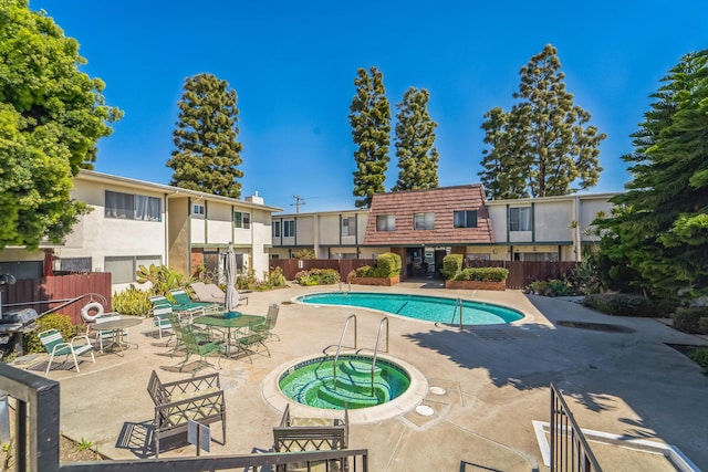 pool featuring a patio area, a hot tub, and fence