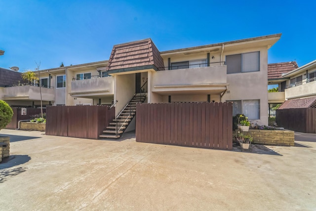 view of front facade featuring stairway, fence, and stucco siding