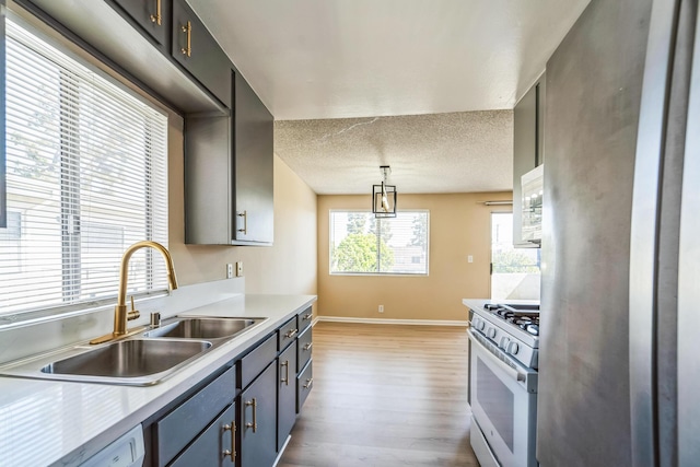 kitchen featuring light wood finished floors, freestanding refrigerator, white gas range, light countertops, and a sink