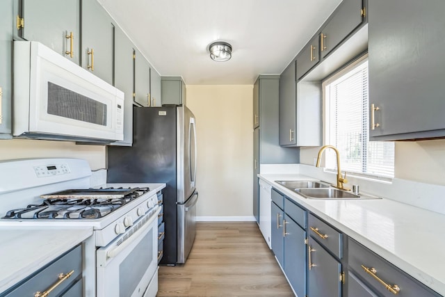 kitchen featuring light wood-style floors, white appliances, light countertops, and a sink