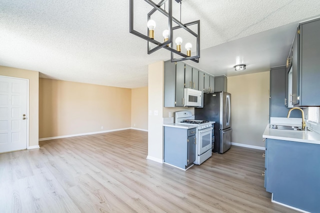 kitchen featuring white appliances, a sink, light wood-style floors, open floor plan, and light countertops