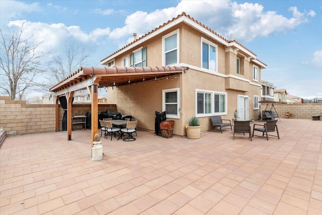 rear view of house featuring a tile roof, stucco siding, outdoor dining area, a fenced backyard, and a patio