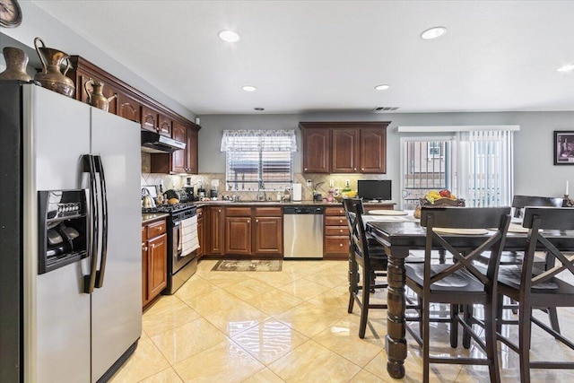 kitchen featuring dark countertops, visible vents, under cabinet range hood, decorative backsplash, and appliances with stainless steel finishes