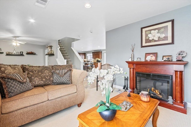 carpeted living area featuring visible vents, a glass covered fireplace, recessed lighting, ceiling fan, and stairs