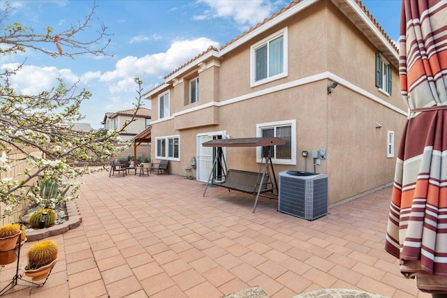 back of property with stucco siding, a tile roof, central AC, fence, and a patio area