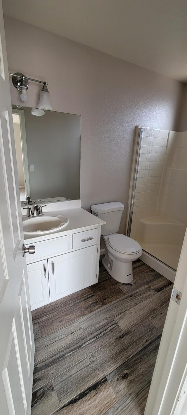 bathroom featuring hardwood / wood-style flooring, vanity, toilet, and walk in shower