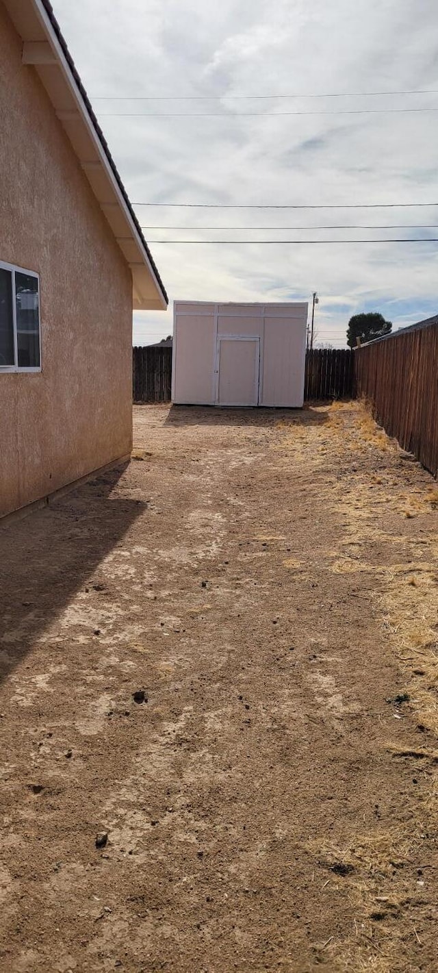 view of yard featuring a storage shed, fence, and an outbuilding