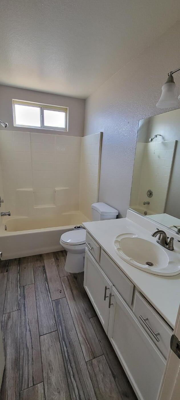 full bathroom featuring vanity, wood-type flooring,  shower combination, and toilet