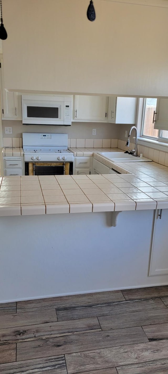 kitchen featuring stove, tile countertops, and white cabinetry