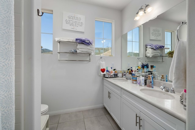 full bathroom featuring toilet, tile patterned floors, double vanity, and a sink