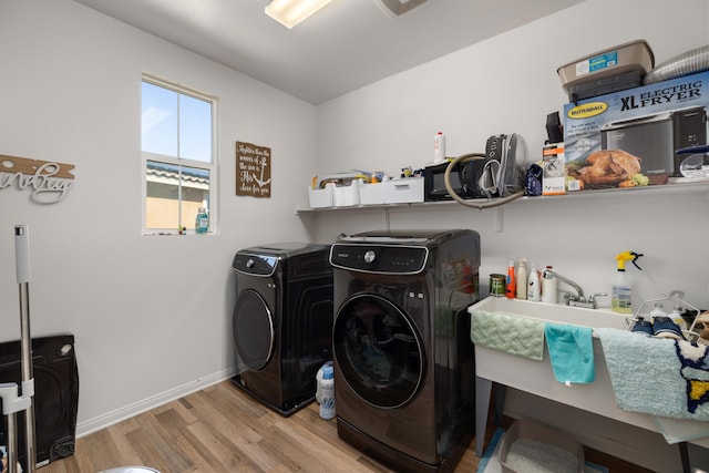 clothes washing area featuring washing machine and clothes dryer, laundry area, baseboards, and wood finished floors