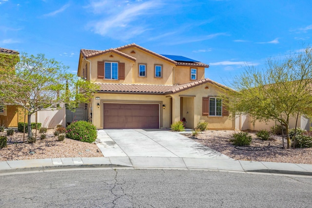 mediterranean / spanish-style home featuring an attached garage, roof mounted solar panels, stucco siding, and driveway