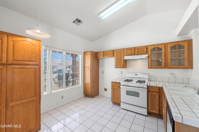 44242 Brandon Thomas Way, Lancaster, CA 93536 - kitchen with gas range gas stove, tile counters, under cabinet range hood, lofted ceiling, and brown cabinets