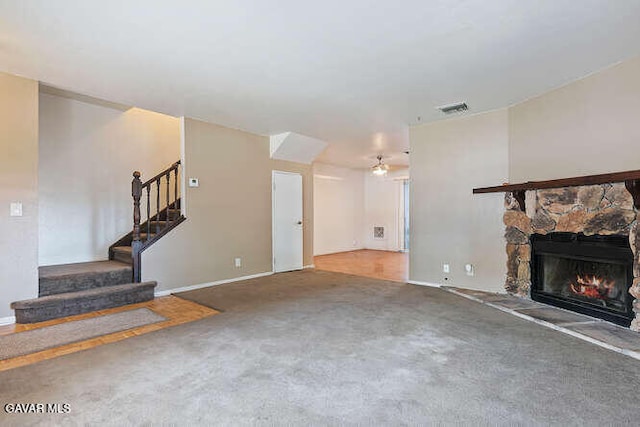 43667 Park Ave, Lancaster, CA 93534 - unfurnished living room featuring a stone fireplace, stairway, carpet floors, and ceiling fan