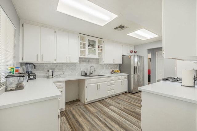 kitchen featuring stainless steel refrigerator with ice dispenser, backsplash, sink, wood-type flooring, and white cabinetry